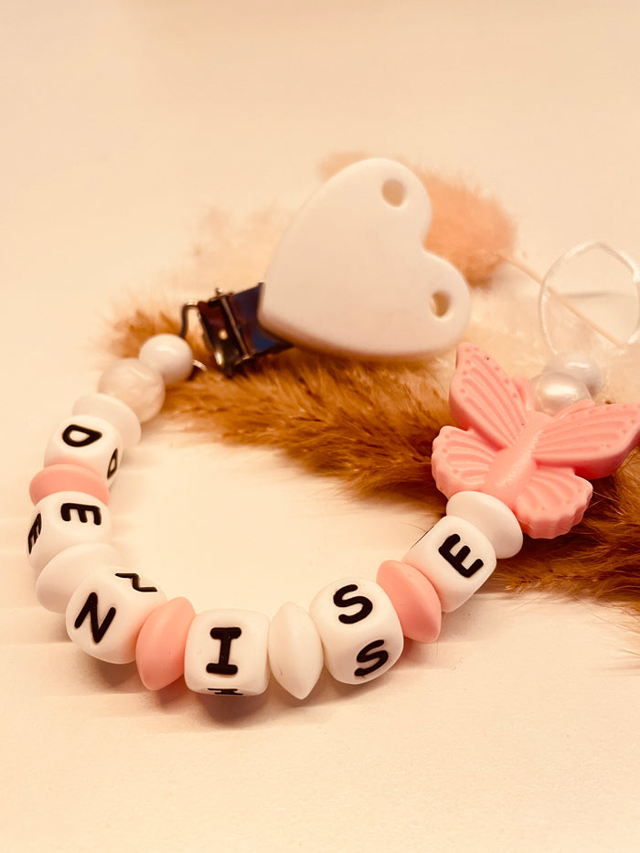 Personalisierte Schnullerkette Schmetterling in rosa, weiß und perlmutt, handgefertigt mit Kunststoff- oder Silikonbuchstaben
